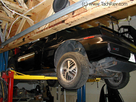 Early model Fiero on lift getting some TLC service